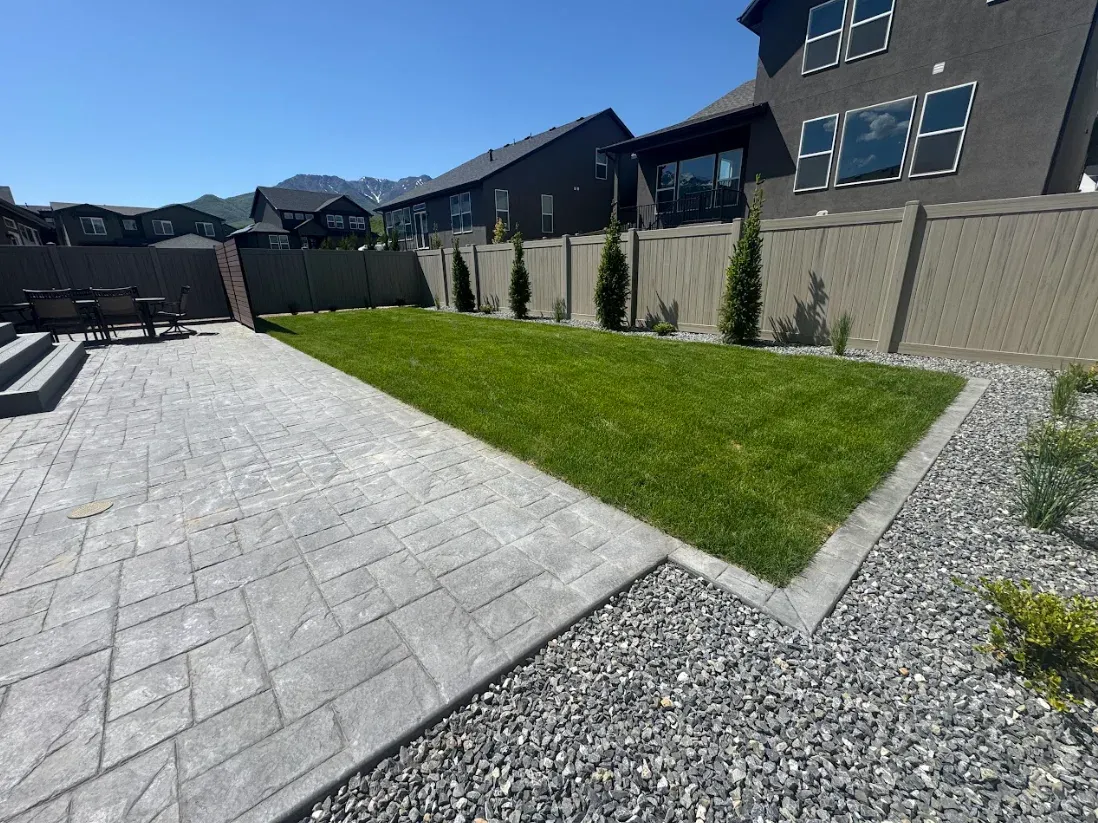 Paver patio running alongside a green lawn and gravel border at a Utah home